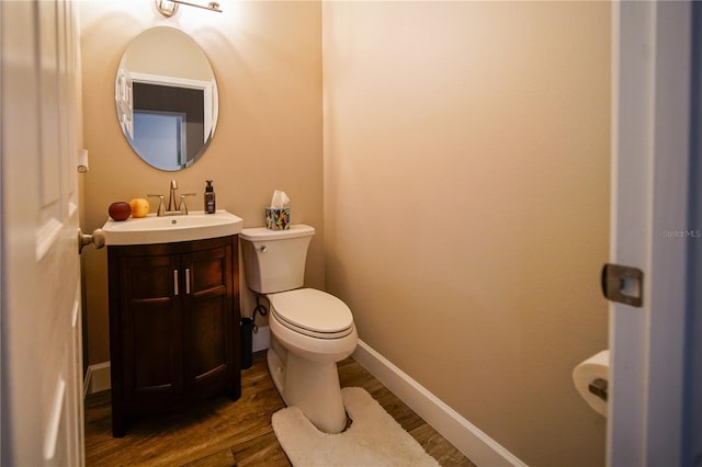 bathroom with toilet, vanity, and wood-type flooring