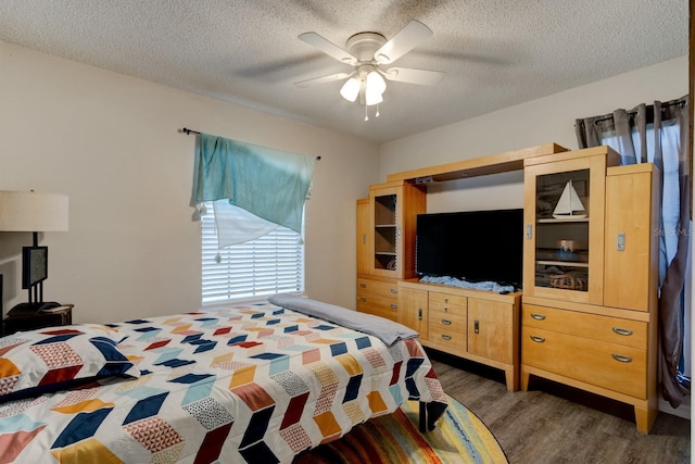 bedroom featuring dark hardwood / wood-style flooring, ceiling fan, and a textured ceiling