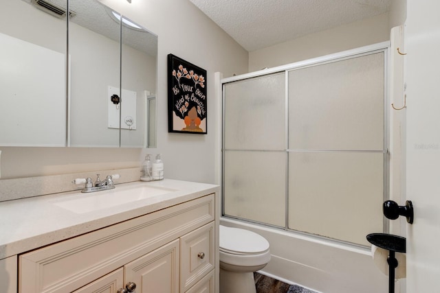 full bathroom featuring bath / shower combo with glass door, vanity, a textured ceiling, and toilet