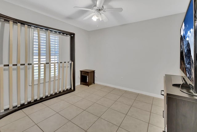 unfurnished room featuring ceiling fan, light tile patterned flooring, and baseboards