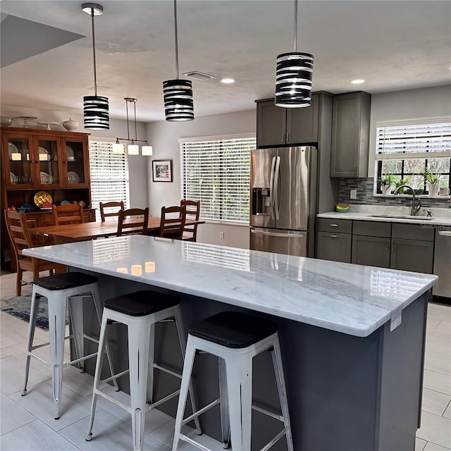 kitchen with stainless steel appliances, a kitchen breakfast bar, sink, and hanging light fixtures