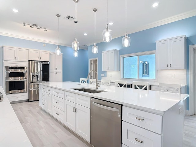 kitchen featuring stainless steel appliances, decorative light fixtures, sink, and white cabinets