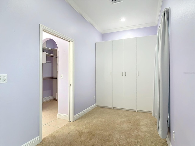 unfurnished bedroom with ornamental molding, light colored carpet, and a closet
