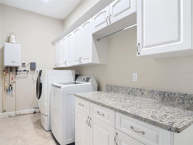 washroom with cabinets, washer and dryer, light tile patterned floors, and water heater