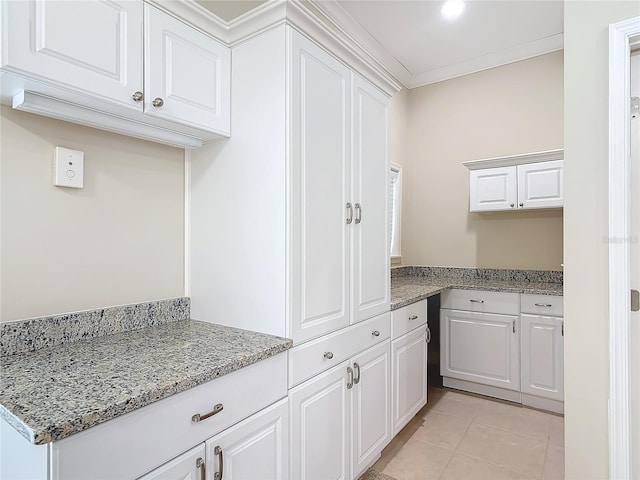 kitchen with white cabinetry, crown molding, light tile patterned flooring, and light stone counters