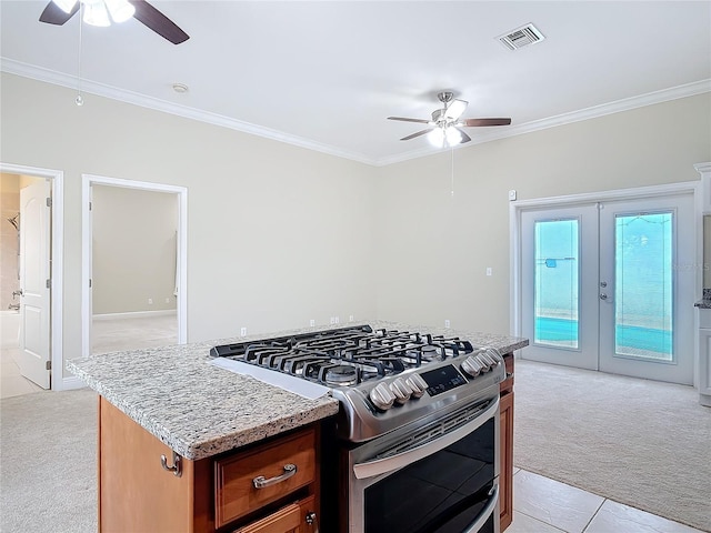 kitchen featuring crown molding, gas range, and light colored carpet