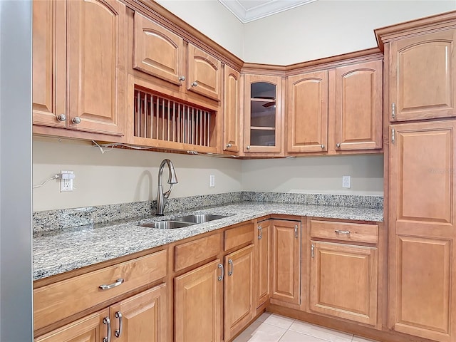 kitchen with light stone counters, sink, ornamental molding, and light tile patterned flooring