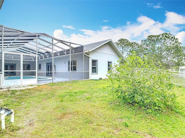 rear view of house with a yard and a lanai
