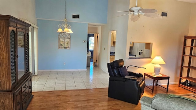 living area featuring light wood-style floors, visible vents, and ceiling fan with notable chandelier