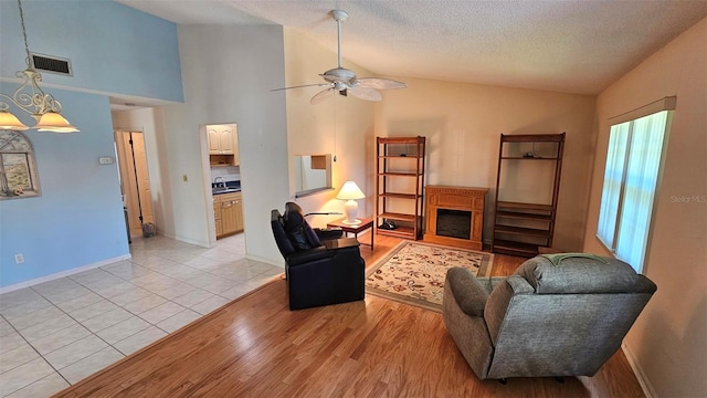 26 Birdie Dr, New Smyrna Beach, FL 32168 - living area with a fireplace, lofted ceiling, visible vents, light wood-style flooring, and a textured ceiling