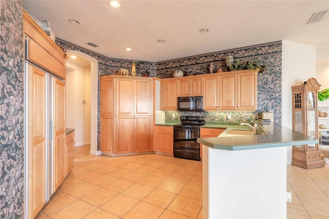 kitchen featuring black appliances, a peninsula, visible vents, and wallpapered walls