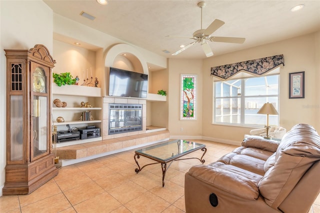 living area featuring light tile patterned floors, ceiling fan, a fireplace, and built in features