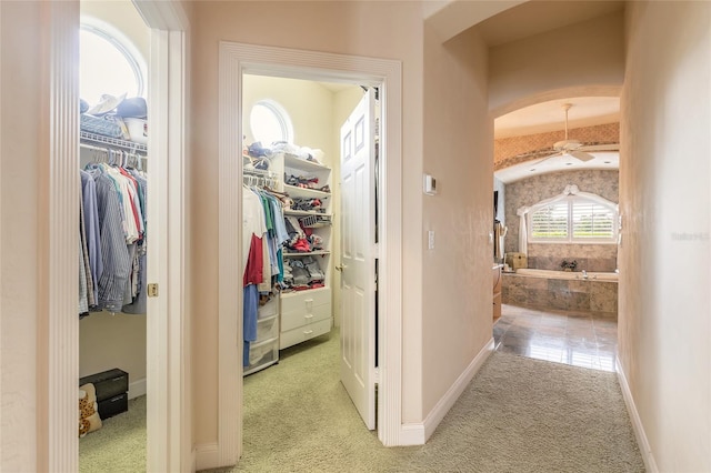 hallway featuring light carpet and baseboards