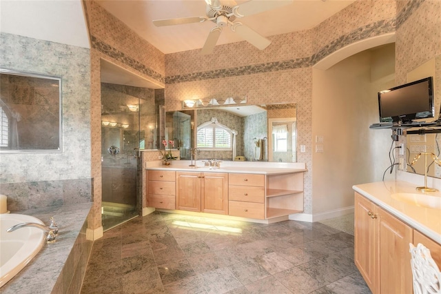 bathroom featuring wallpapered walls, two vanities, a bath, and a stall shower