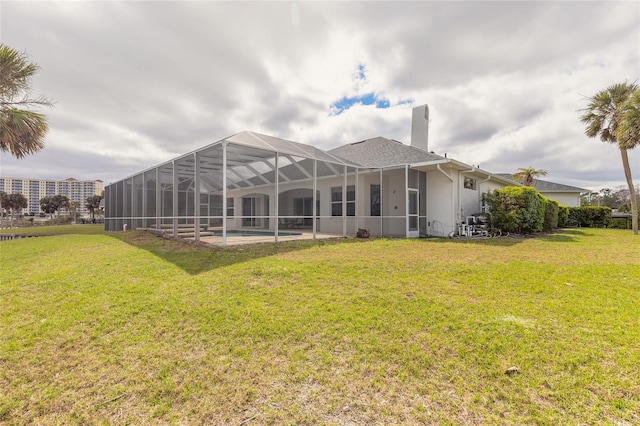 rear view of property featuring a lanai, a chimney, an outdoor pool, and a lawn