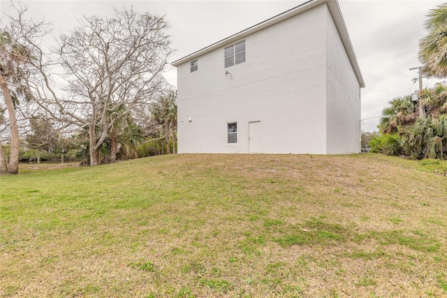 back of house with a yard and stucco siding