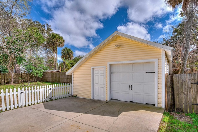 detached garage with concrete driveway and fence