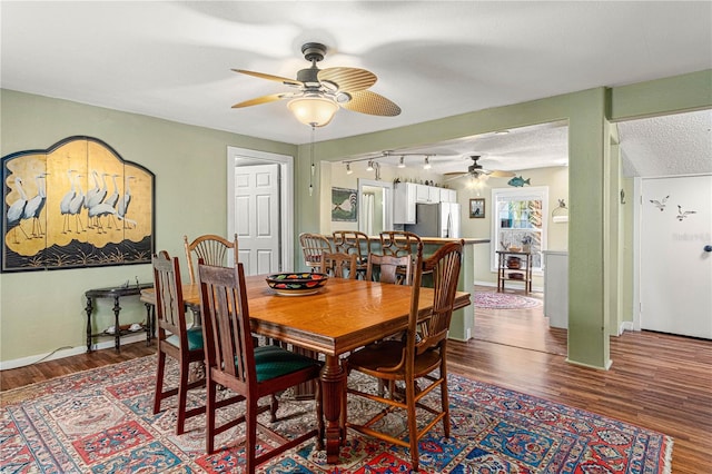 dining room featuring a textured ceiling, wood finished floors, a ceiling fan, and baseboards