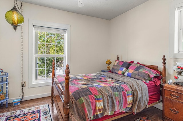 bedroom featuring dark wood-type flooring, multiple windows, and baseboards