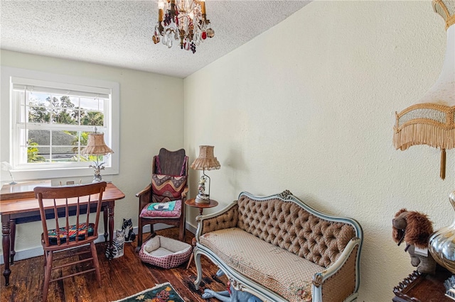 living area with dark wood-type flooring, a chandelier, a textured wall, and a textured ceiling