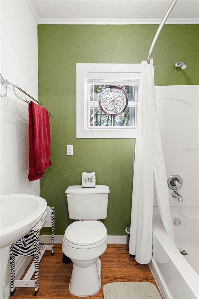 bathroom featuring toilet, shower / tub combo, baseboards, and wood finished floors