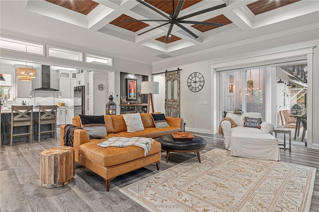 living area featuring a ceiling fan, wood finished floors, crown molding, and a barn door