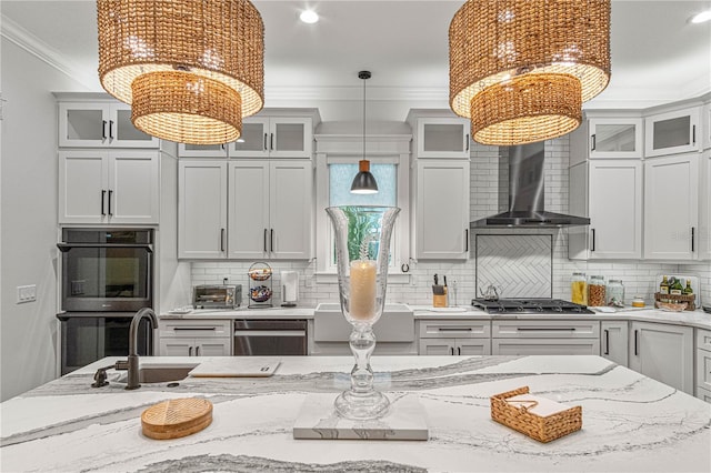 kitchen featuring a notable chandelier, appliances with stainless steel finishes, decorative backsplash, wall chimney exhaust hood, and crown molding