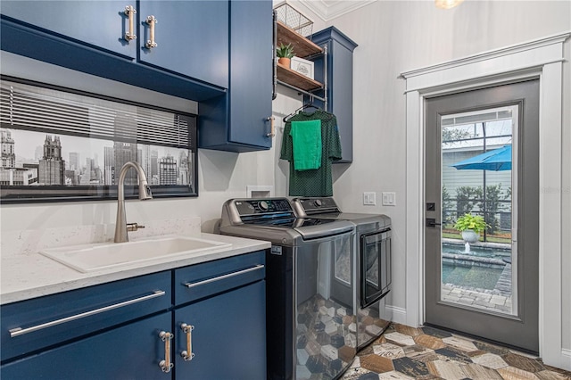 washroom featuring cabinet space, baseboards, washer and clothes dryer, and a sink