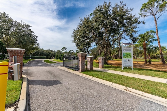 view of street featuring a gate, curbs, sidewalks, and a gated entry