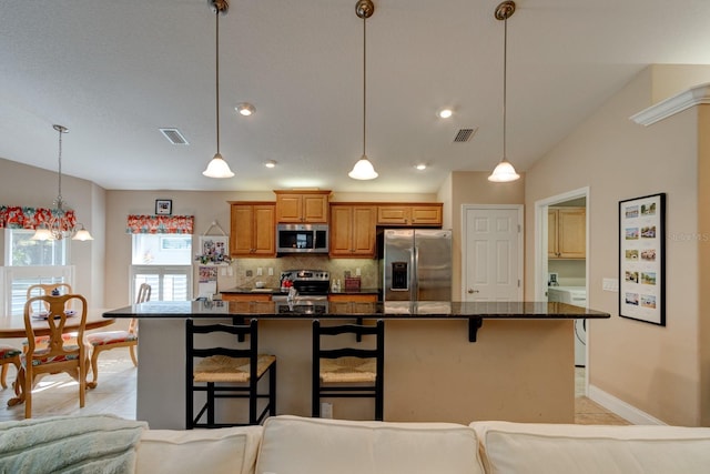 kitchen featuring tasteful backsplash, a center island with sink, visible vents, a kitchen breakfast bar, and stainless steel appliances