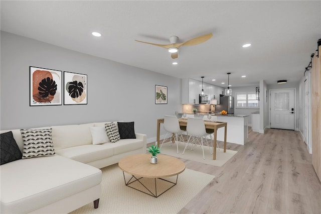325 N Causeway Unit B101, New Smyrna Beach, FL 32169 - living room with a barn door, light wood finished floors, recessed lighting, and a ceiling fan