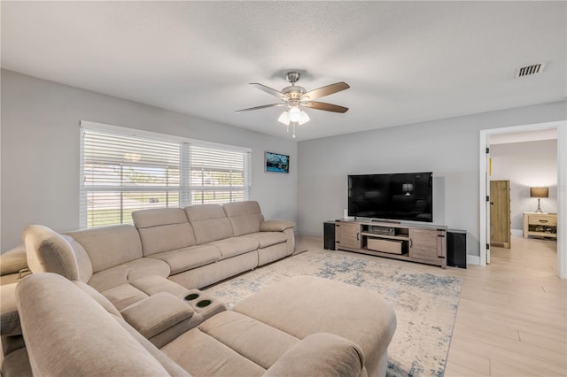 living area with baseboards, visible vents, a ceiling fan, a textured ceiling, and light wood-style floors