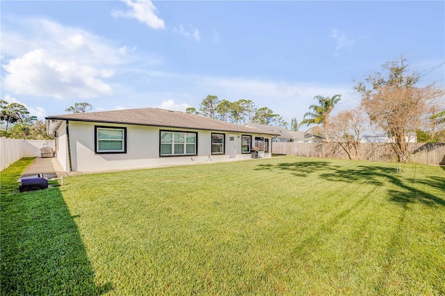 rear view of property with a lawn, a patio area, a fenced backyard, and stucco siding