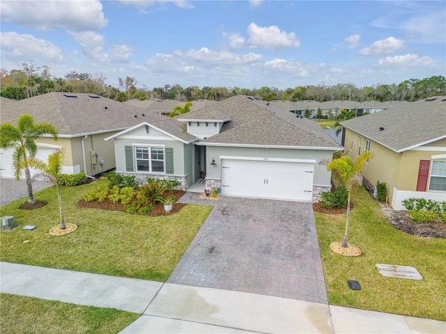 ranch-style home featuring a garage, a residential view, decorative driveway, and a front yard