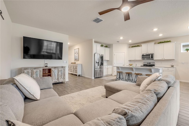 living area featuring ceiling fan, recessed lighting, visible vents, baseboards, and light wood finished floors