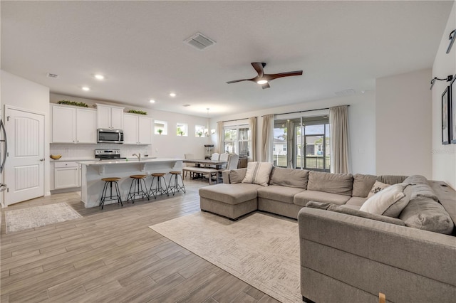 living area with a wealth of natural light, light wood-type flooring, visible vents, and recessed lighting