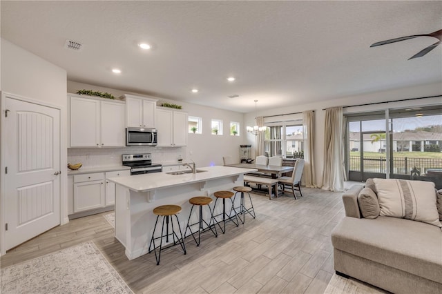 kitchen with hanging light fixtures, a center island with sink, appliances with stainless steel finishes, and light countertops