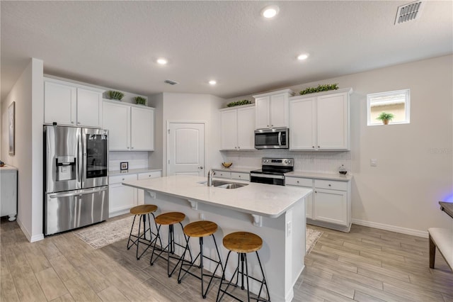 kitchen featuring light countertops, appliances with stainless steel finishes, a sink, and white cabinetry