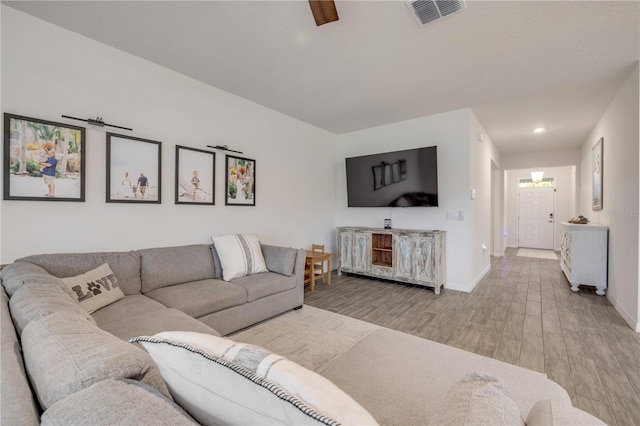 living area featuring light wood-type flooring, visible vents, and baseboards