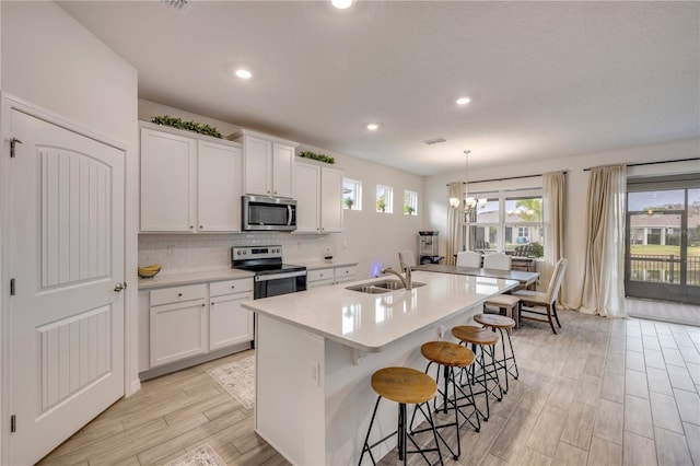 kitchen with a sink, white cabinets, stainless steel appliances, and light countertops