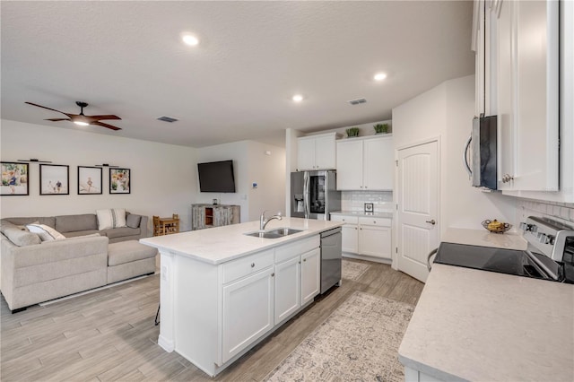 kitchen with white cabinets, a center island with sink, appliances with stainless steel finishes, and open floor plan