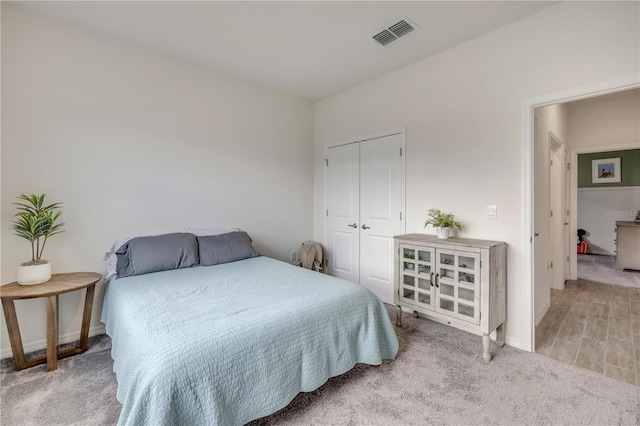 bedroom with light carpet, a closet, visible vents, and baseboards