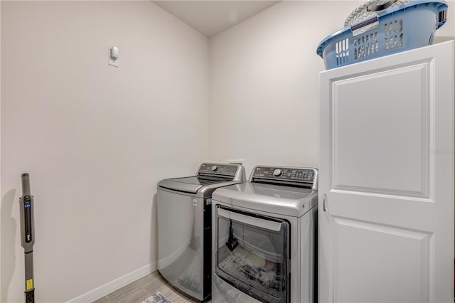 laundry area with light wood-type flooring, laundry area, baseboards, and washing machine and clothes dryer