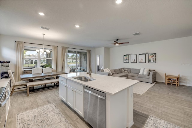 kitchen with light countertops, stainless steel dishwasher, white cabinets, a sink, and an island with sink