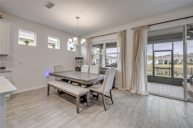 dining space featuring baseboards, visible vents, an inviting chandelier, a textured ceiling, and wood finish floors