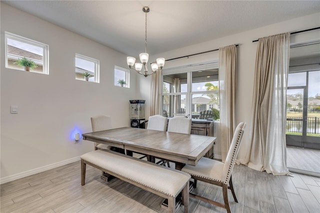 dining room featuring light wood-type flooring, plenty of natural light, baseboards, and a chandelier