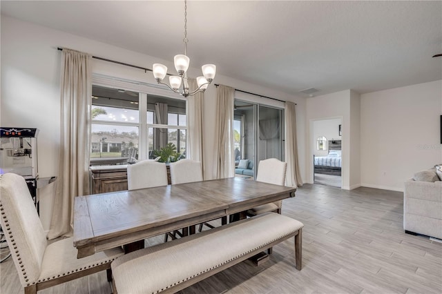 dining room with baseboards, light wood-style flooring, visible vents, and an inviting chandelier