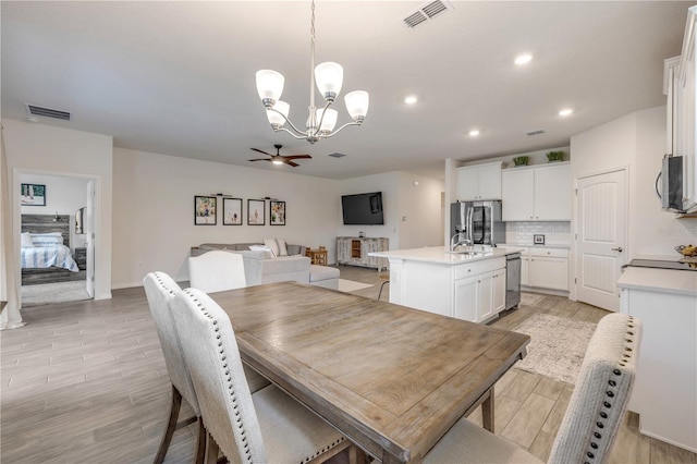 dining space featuring light wood-style floors, recessed lighting, visible vents, and ceiling fan with notable chandelier