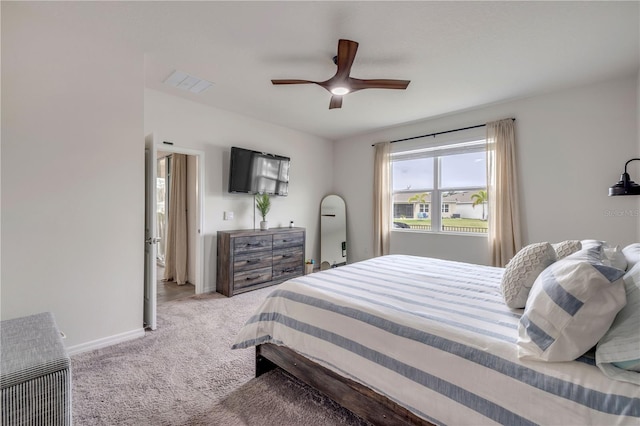 bedroom with ceiling fan, light carpet, visible vents, baseboards, and heating unit