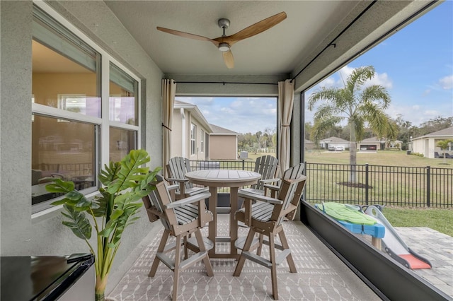 sunroom / solarium featuring ceiling fan and a residential view